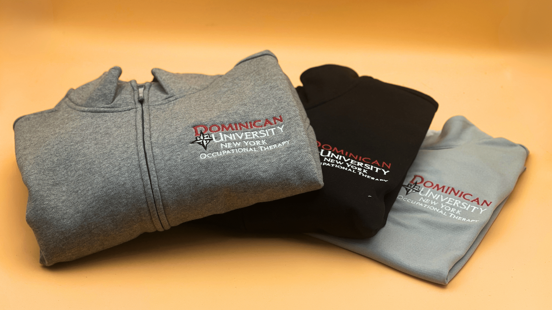 Custom university spirit wear featuring embroidered logos on zip-up and crewneck sweatshirts.