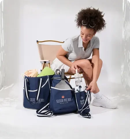 Woman organizing branded tote bags with beach essentials, showcasing custom logo bags for promotional and lifestyle use