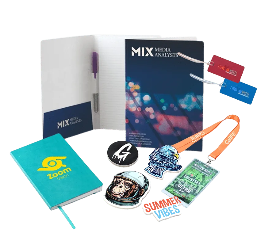 A professional mockup of diverse branded promotional materials and corporate stationary. It includes a dark-covered "Mix Media Analysts" padfolio with an internal pen holder, a teal "Zoom" notebook, colorful lanyards, business cards, and custom stickers or patches. All of these are arranged in a transparent background.
