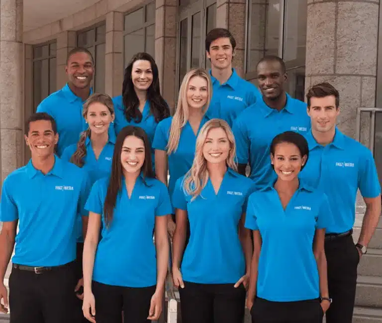 A group of ten diverse professionals wearing matching bright blue polo shirts and dark trousers with a logo on left chest.
