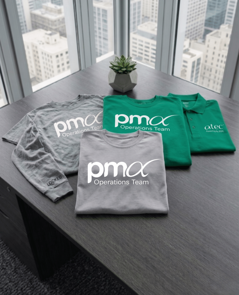 Custom corporate apparel collection featuring branded T-shirts, long sleeve shirts, and embroidered polos displayed on an office conference table.