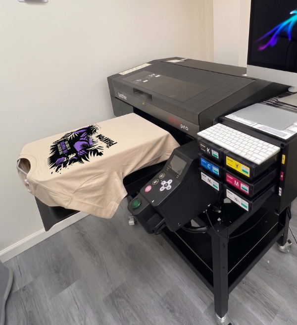 Cream T-shirt with a colorful graphic being printed on a Brother DTG printer.